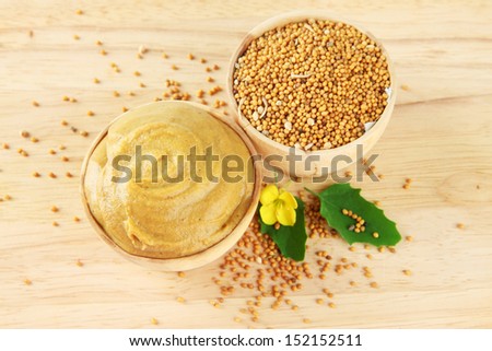 Mustard with seeds and mustard flower on wooden background