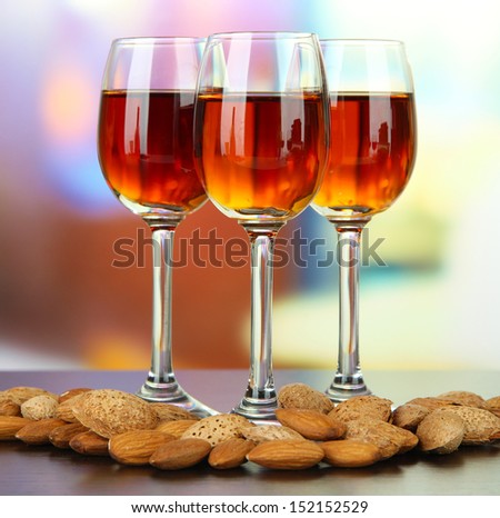 Glasses of amaretto liquor and roasted almonds, on bright background