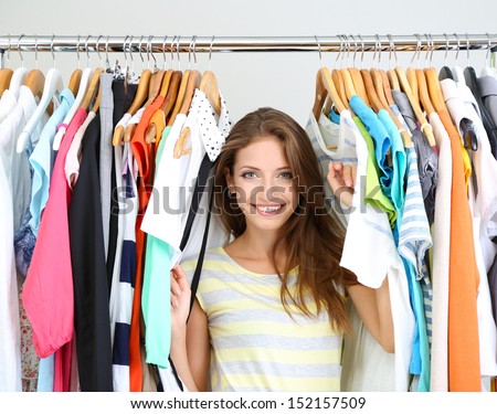 Beautiful young woman near rack with hangers