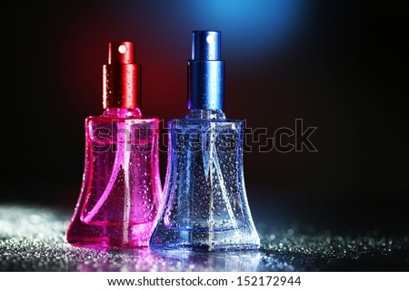 Women perfume in beautiful bottles on dark background with color light