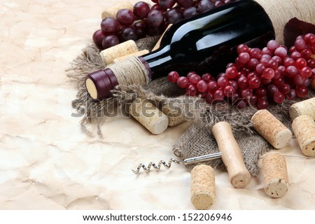 Bottle of wine, grapes and corks on old paper background