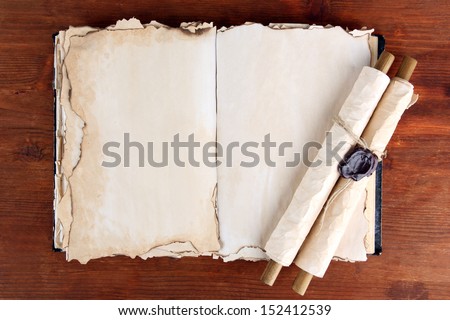 Open old book and scrolls on wooden background