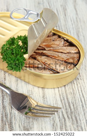 Open tin can with sardines, on wooden background