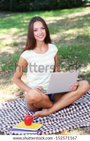 Beautiful young girl with laptop in park