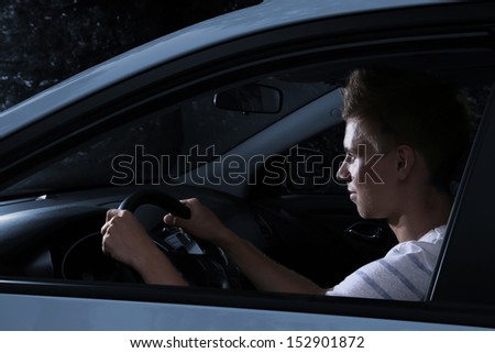 Young man driving in his car at night