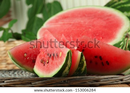Ripe watermelons on wicker tray  on table on wooden background