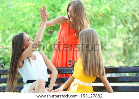 Three beautiful young woman  sitting on bench in summer park