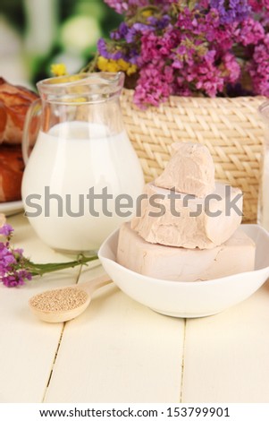 Dry yeast with pastry and baking ingredients on wooden table on natural background