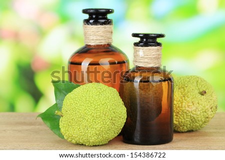 Osage Orange fruits (Maclura pomifera) and medicine bottles, on wooden table, on nature background