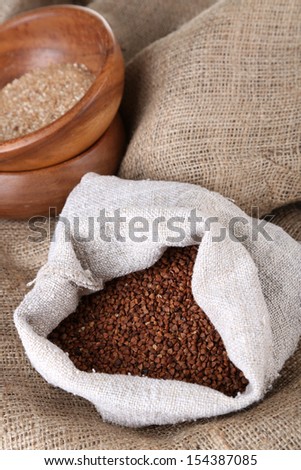 Cloth bag with buckwheat and wooden bowls closeup