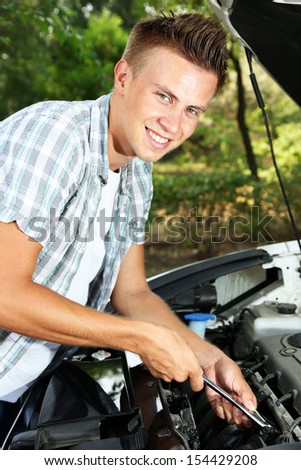 Young driver repairing car engine outdoors