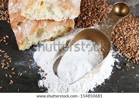 The wholemeal flour in scoop on wooden table on sackcloth background
