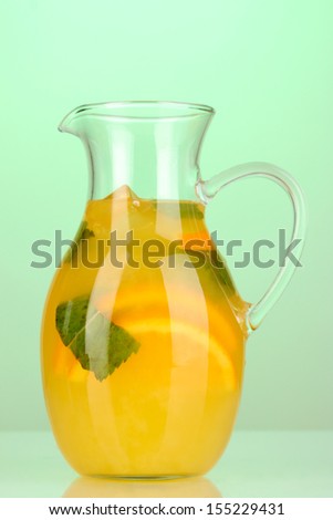 Orange lemonade in pitcher on turquoise background