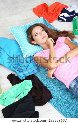 Beautiful girl lying on floor and thinking what to dress in walk-in closet