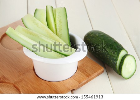 Bright fresh cucumber cut up slices in bowl on wooden table close-up