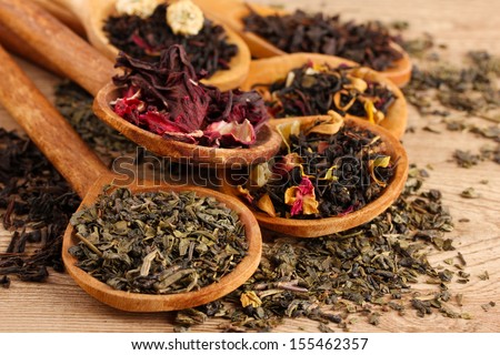 Assortment Of Dry Tea In Spoons, On Wooden Background