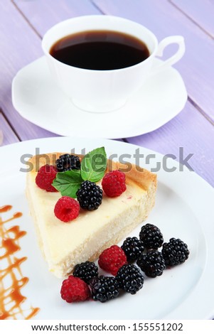 Slice of cheesecake with raspberry and blackberry on plate, on bright background
