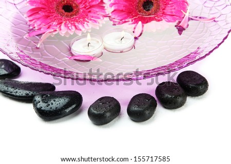 Spa stones, gerbera flowers and candles on water, isolated on white