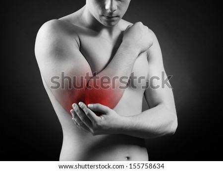 Young man with elbow pain, on red background
