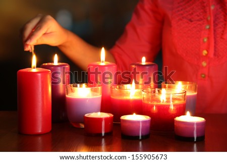 Woman lights candles on bright background