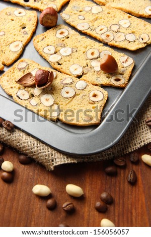 Biscotti with hazelnuts, on  dripping pan, on wooden background