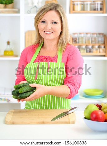 Happy smiling woman in kitchen  holding fresh vegetables in her hands