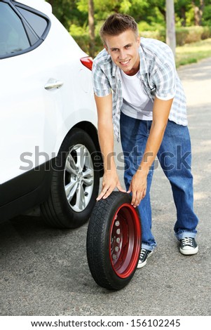 Man driver having trouble at road changing wheel