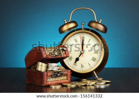 Antique clock and coins on wooden table on dark color background