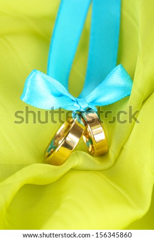 Wedding rings tied with ribbon on bright fabric