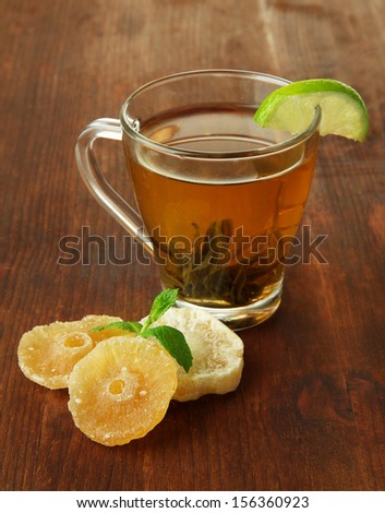 Transparent cup of green tea with candied fruit on wooden background