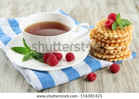 Cup of tea with cookies and raspberries on table close-up