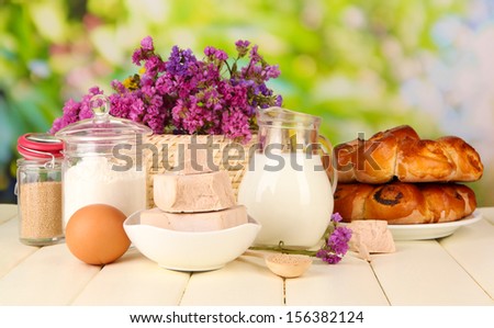 Dry yeast with pastry and baking ingredients on wooden table on natural background