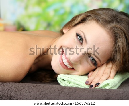 Beautiful young woman on massage table on natural background