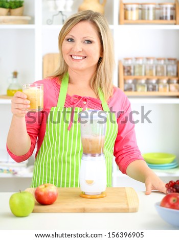 Happy smiling woman in kitchen preparing fresh fruit cocktail