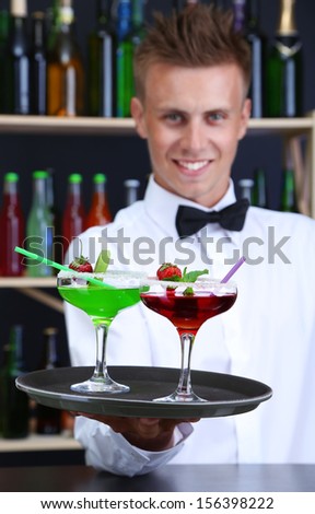 Portrait of handsome barman with different cocktails cocktail, at bar
