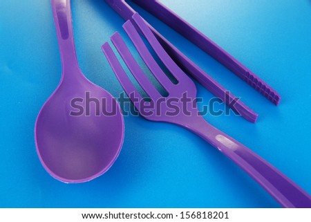 Plastic kitchen utensils on blue background