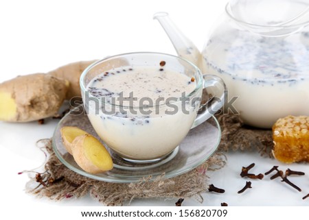 Teapot and cup of tea with milk and spices on sackcloth isolated on white