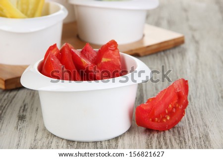 Bright fresh vegetables cut up slices in bowls on wooden table close-up
