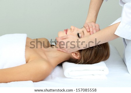 Beautiful young woman during facial massage in cosmetic salon close up