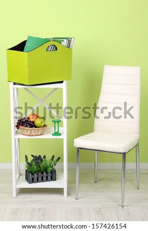 Magazines and folders in green box on shelf in room