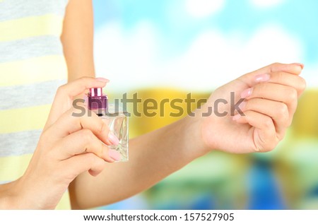 Woman testing perfume on bright background