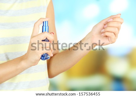 Woman testing perfume on bright background