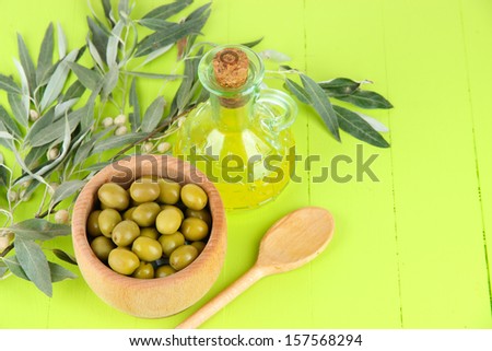 Olive oil branch and olive in bowl on wooden table