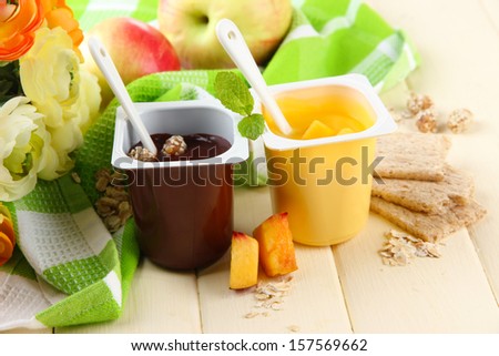 Tasty   cream desserts with pieces of fresh fruits, cookies and flakes,on color  wooden background