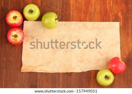 Old paper and small apples on wooden background