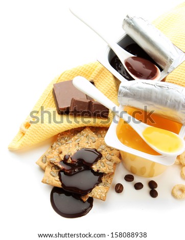 Tasty desserts in open plastic cups and honey combs, fruits and flakes on napkin, isolated on white