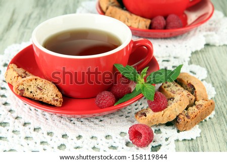 Cups of tea with cookies and raspberries on table close-up