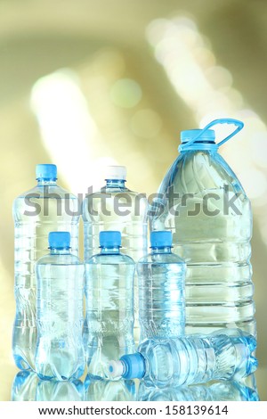 Water in different bottles on light background