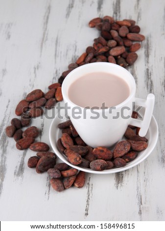 Cocoa drink and cocoa beans on wooden background