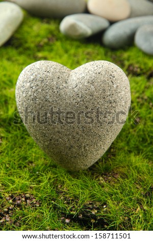 Grey stone in shape of heart, on grass background
